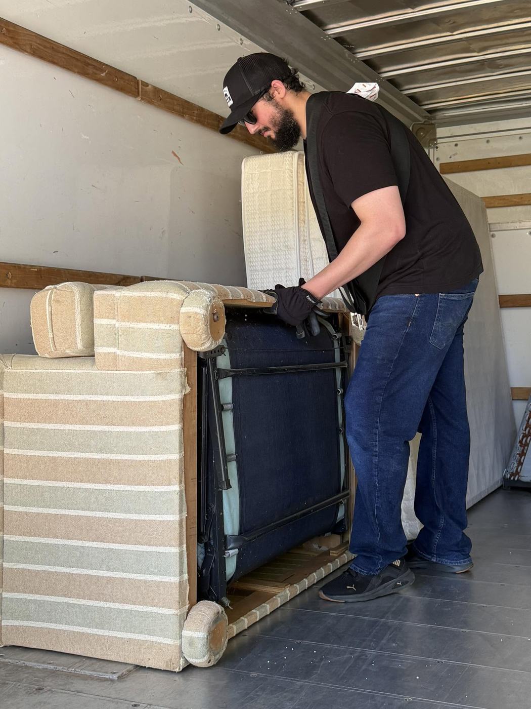OverKnight crew member Mike loading a sleeper sofa into the junk removal truck